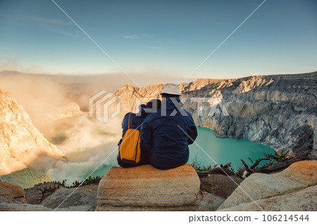 Couple tourist travel sitting on top of Kawah Ijen and sulfur smoke in the morning 106214544