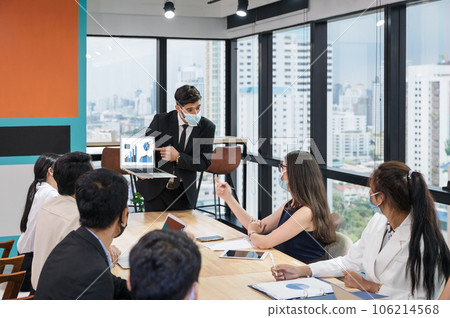 Businessman wearing face mask with presentation of business plan on laptop, corporate business meeting in modern office 106214568