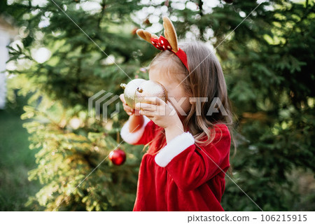 Christmas in july. Child waiting for Christmas in wood in summer. portrait of little girl in red dress decorating christmas tree. winter holidays and people concept. Merry Christmas and Happy Holidays 106215915