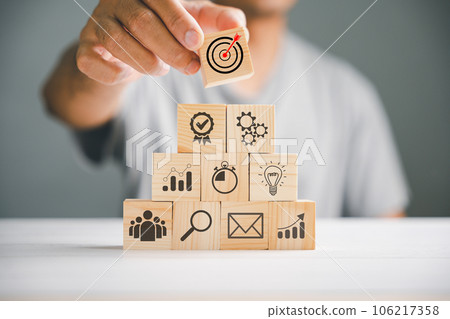 Hand stacking wooden blocks on a table, emphasizing the significance of a business strategy and action plan. Business development concept with copy space for customization. 106217358