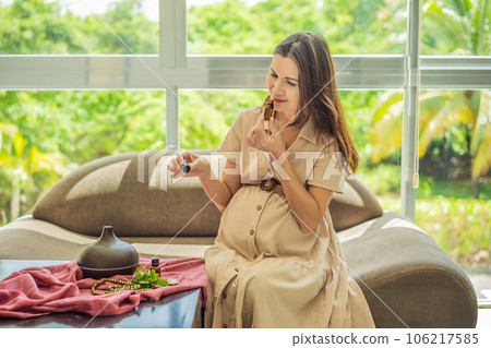 A serene moment captured as a pregnant woman after 40 embraces the soothing benefits of aroma oils and an aroma diffuser, enhancing her pregnancy journey with relaxation and tranquility 106217585