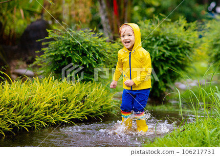 Kids in puddle in autumn rain. Waterproof wear 106217731
