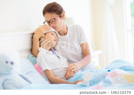 Sick child in bed. Mother checking on unwell kid. 106218379