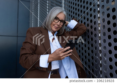 60 years old successful slender gray-haired business woman dressed in a stylish brown jacket is 60 years old successful slender gray-haired business woman dressed in a stylish brown jacket is 106218928