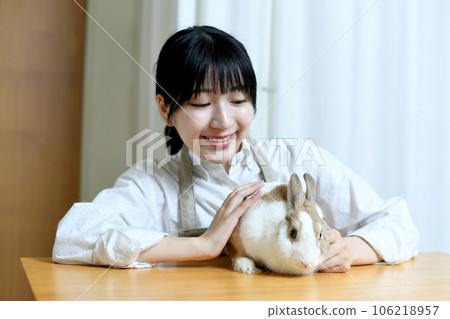 A young woman in an apron who touches a rabbit A young woman in an apron who touches a rabbit 106218957