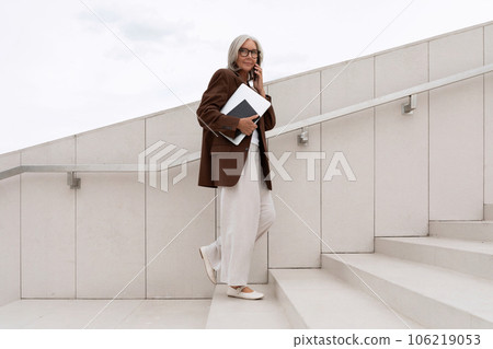 a gray-haired middle-aged woman with a bob hairstyle dressed in a jacket and trousers walks around a gray-haired middle-aged woman with a bob hairstyle dressed in a jacket and trousers walks around 106219053