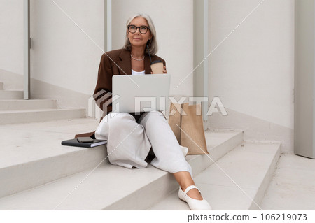 stylish successful mature business woman with gray hair holding online meeting on laptop while 106219073