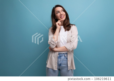 dreamy brunette young female adult in shirt and jeans on blue background 106219611