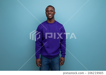handsome young american man in blue sweatshirt on blue background with copy space 106219985