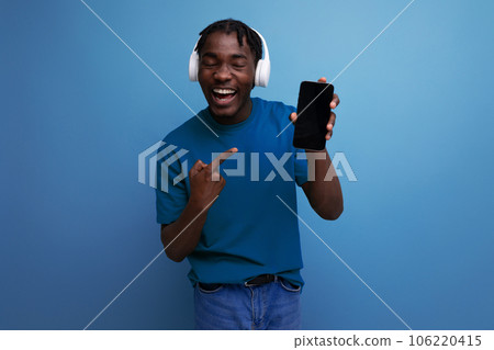 positive young man listening to music using headphones and smartphone 106220415