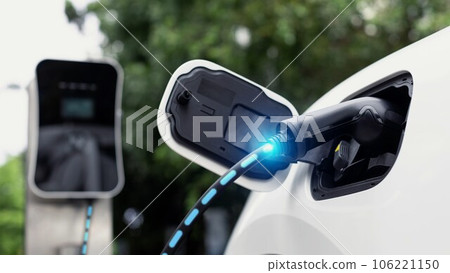 Electric car plugged in with charging station in eco green park. Peruse 106221150