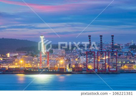 View of Lisbon port with moored sea container ship with port cranes in the evening twilight over Tagus river. Lisbon, Portugal View of Lisbon port with moored sea container ship with port cranes in the evening twilight over Tagus river. Lisbon, Portugal 106221381