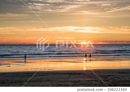 Atlantic ocean sunset with photographer silhouette taking images of surging waves at Fonte da Telha beach, Costa da Caparica, Portugal 106221384
