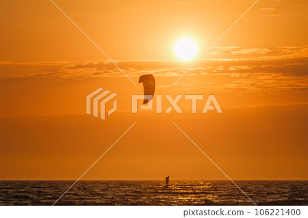 Foiling kiteboarding kitesurfing kiteboarder (kitesurfer) silhouette in the Atlantic ocean on sunset. Fonte da Telha beach, Costa da Caparica, Portugal 106221400