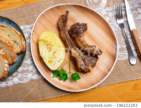 Appetizing rosy and barbecued lamb ribs seasoned and served with fresh parsley and potatoes on plate. 106222263