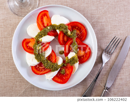 Caprese salad with mozzarella, tomatoes and pesto sauce on plate Caprese salad with mozzarella, tomatoes and pesto sauce on plate 106222402