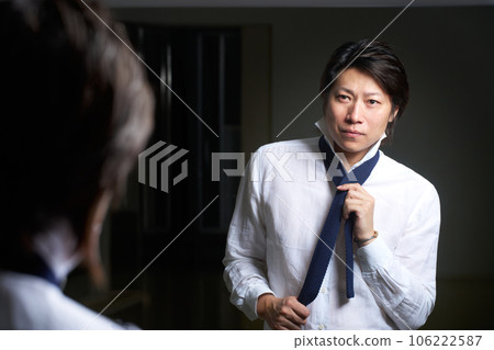 Business person tightening a tie while looking in the mirror 106222587