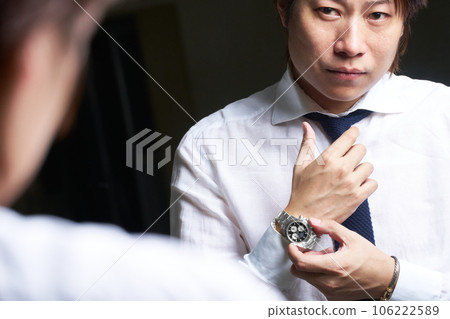 Business person wearing a watch in front of a mirror 106222589