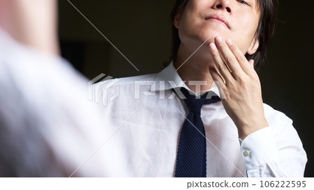 一個男人一邊照鏡子一邊檢查自己的皮膚 106222595