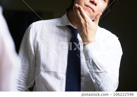 一個男人一邊照鏡子一邊檢查自己的皮膚 106222596