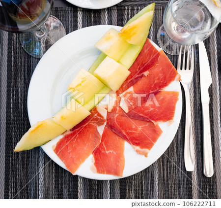 Mediterranian appetizers melon with ham on white plate. 106222711