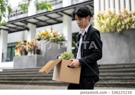 A stressed and sad Asian businessman is walking down the stairs after losing his job. 106225238