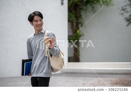 A handsome and smiling young Asian male student is walking down his campus building A handsome and smiling young Asian male student is walking down his campus building 106225286