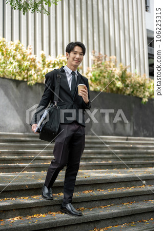 A handsome Asian businessman walking down the stairs in front of the building. 106225315
