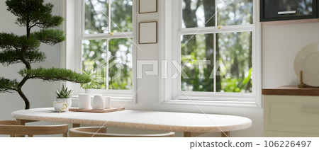 A beautiful white Scandinavian dining room with a dining table against the window 106226497