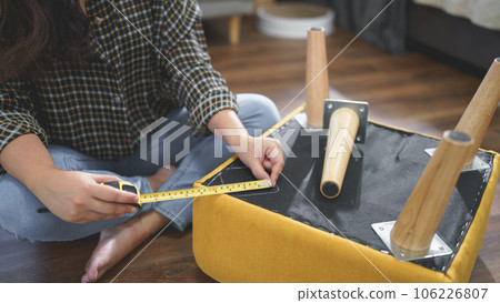 Women use measure tape equipment to measuring size for assembly leg of chair while making furniture 106226807