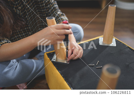 Women use screwdriver equipment to tighten screw while assembling leg of chair to making furniture Women use screwdriver equipment to tighten screw while assembling leg of chair to making furniture 106226811