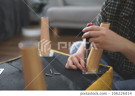 Women use screwdriver equipment to tighten screw while assembling leg of chair to making furniture Women use screwdriver equipment to tighten screw while assembling leg of chair to making furniture 106226814