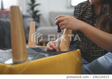 Women use screwdriver equipment to tighten screw while assembling leg of chair to making furniture Women use screwdriver equipment to tighten screw while assembling leg of chair to making furniture 106226815