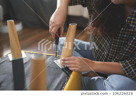 Women tighten screw with screwdriver equipment for repairing leg of chair and assembling furniture 106226828