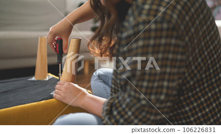 Women tighten screw with screwdriver equipment for repairing leg of chair and assembling furniture Women tighten screw with screwdriver equipment for repairing leg of chair and assembling furniture 106226831