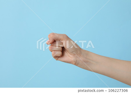Female hand clenched into a fist on a light blue background Female hand clenched into a fist on a light blue background 106227306