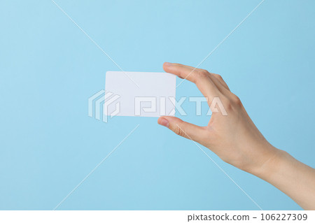 A white blank sheet of paper in the hands of a woman, on a blue background A white blank sheet of paper in the hands of a woman, on a blue background 106227309