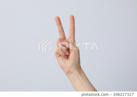 Female hand showing two fingers on a light background Female hand showing two fingers on a light background 106227327