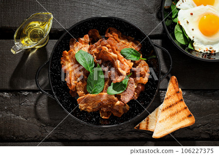 Tasty breakfast and delicious meat food concept - fried bacon Tasty breakfast and delicious meat food concept - fried bacon 106227375