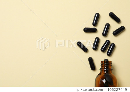 Tablets of activated carbon and a glass bottle on a light background 106227449