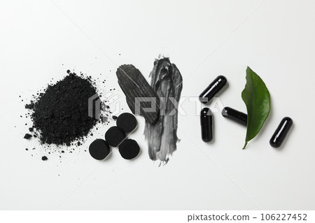Tablets of activated carbon and a piece of coal on a light background 106227452