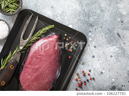 Raw beef steak sirloin fillet sealed in vacuum tray with pepper,rosemary and barbeque fork 106227781