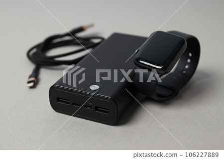 Powerbank, cord and smart clock on gray background, close up 106227889