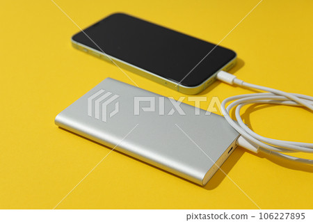 Powerbank, cord and smartphone on yellow background Powerbank, cord and smartphone on yellow background 106227895