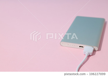 Powerbank with USB cord on pink background, space for text 106227899