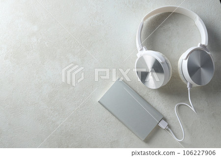 Powerbank, cord and headphones on gray background, space for text Powerbank, cord and headphones on gray background, space for text 106227906