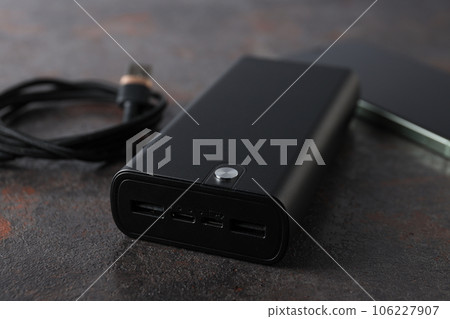Powerbank, cord and smartphone on gray background, close up Powerbank, cord and smartphone on gray background, close up 106227907