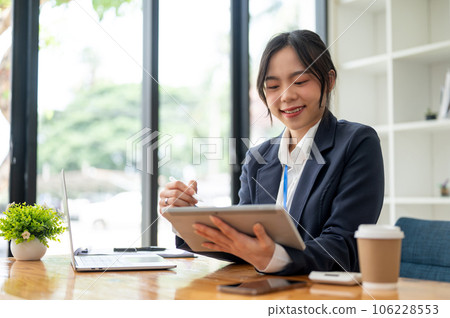 A beautiful Asian businesswoman or female accountant is using her tablet at her desk 106228553