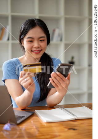 A beautiful Asian woman enjoys shopping online at home and pay with her credit card. 106228649