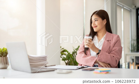 A successful female CEO is sipping coffee, looking out the window, and daydreaming 106228972